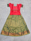 Coral pink semi silk top with teal green bridal silk skirt pattu pavadai for girls featuring puff hand sleeves, waist belt design and double chain stone neck work by Sri Thulir Tex