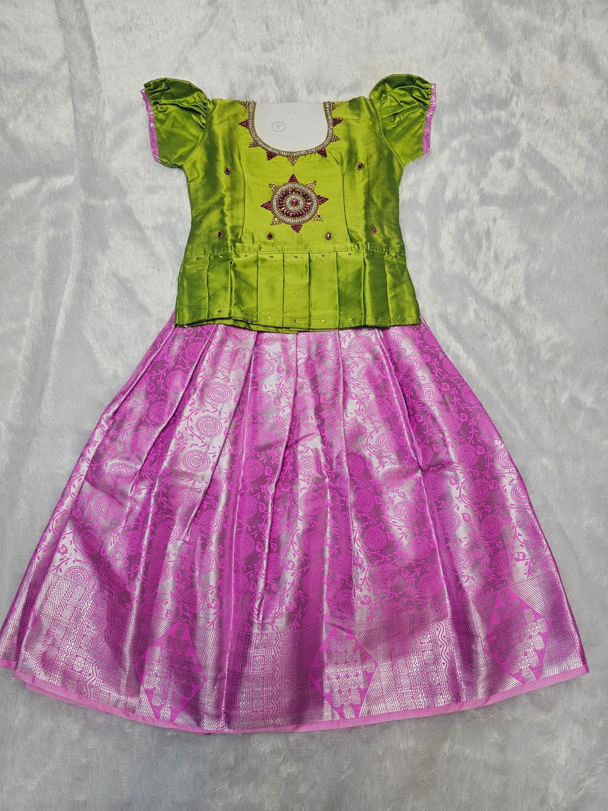 Green semi silk top with pink bridal silk skirt pattu pavadai for girls featuring puff sleeves and double chain stone neck work, traditional South Indian ethnic wear by Sri Thulir Tex