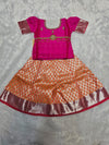 Hot pink semi silk top with orange bridal silk skirt pattu pavadai for girls featuring puff hand sleeves, waist belt detailing and double chain stone neck work by Sri Thulir Tex