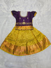 Purple semi silk top with green bridal silk skirt pattu pavadai for girls featuring puff hand sleeves, waist belt detailing and double chain stone neck stone work by Sri Thulir Tex