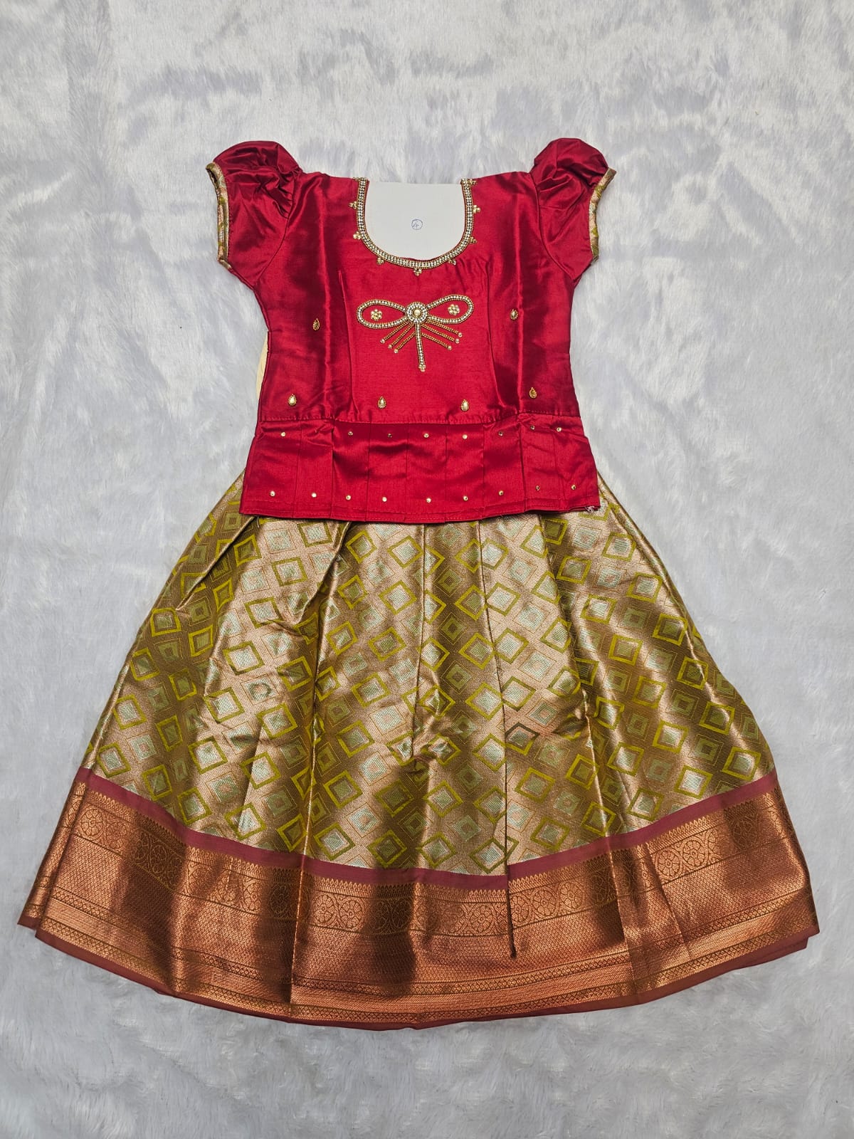 Red semi silk top with gold bridal silk skirt pattu pavadai for girls featuring puff sleeves and double chain stone neck work, traditional South Indian ethnic wear by Sri Thulir Tex