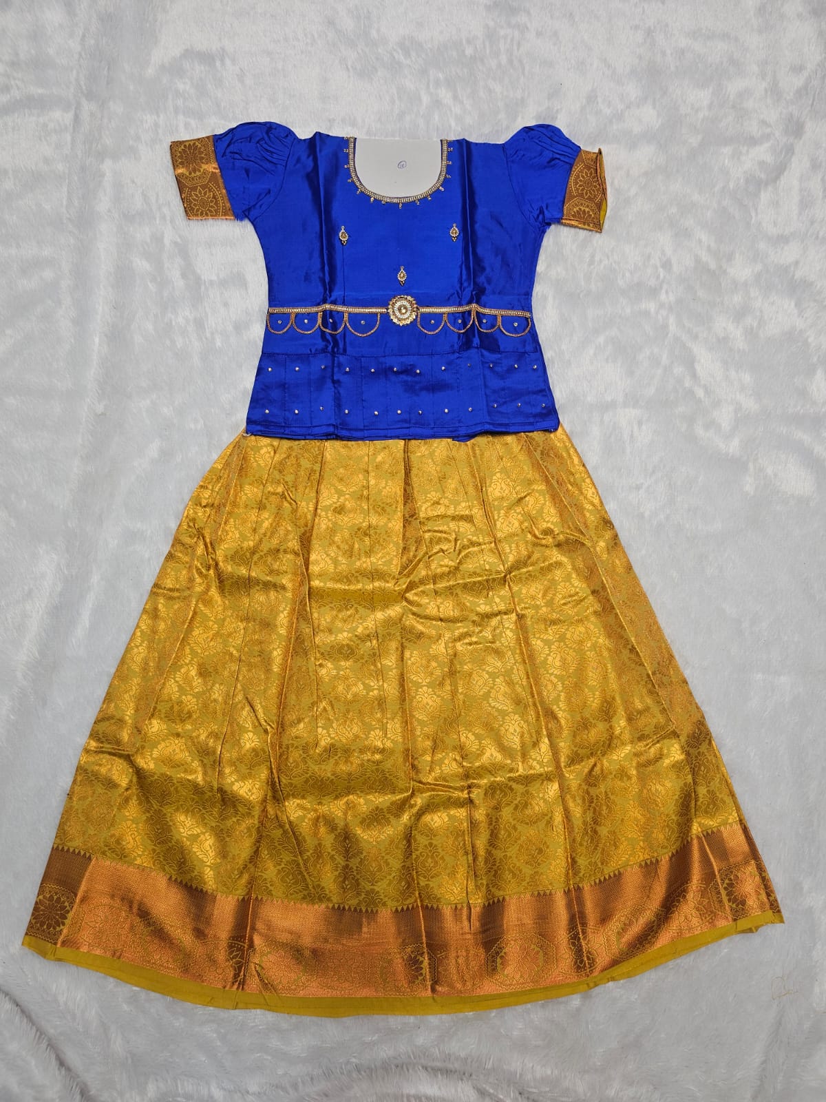 Royal blue semi silk top with golden yellow bridal silk skirt pattu pavadai for girls featuring puff sleeves, waist belt detailing and double chain stone neck work by Sri Thulir Tex