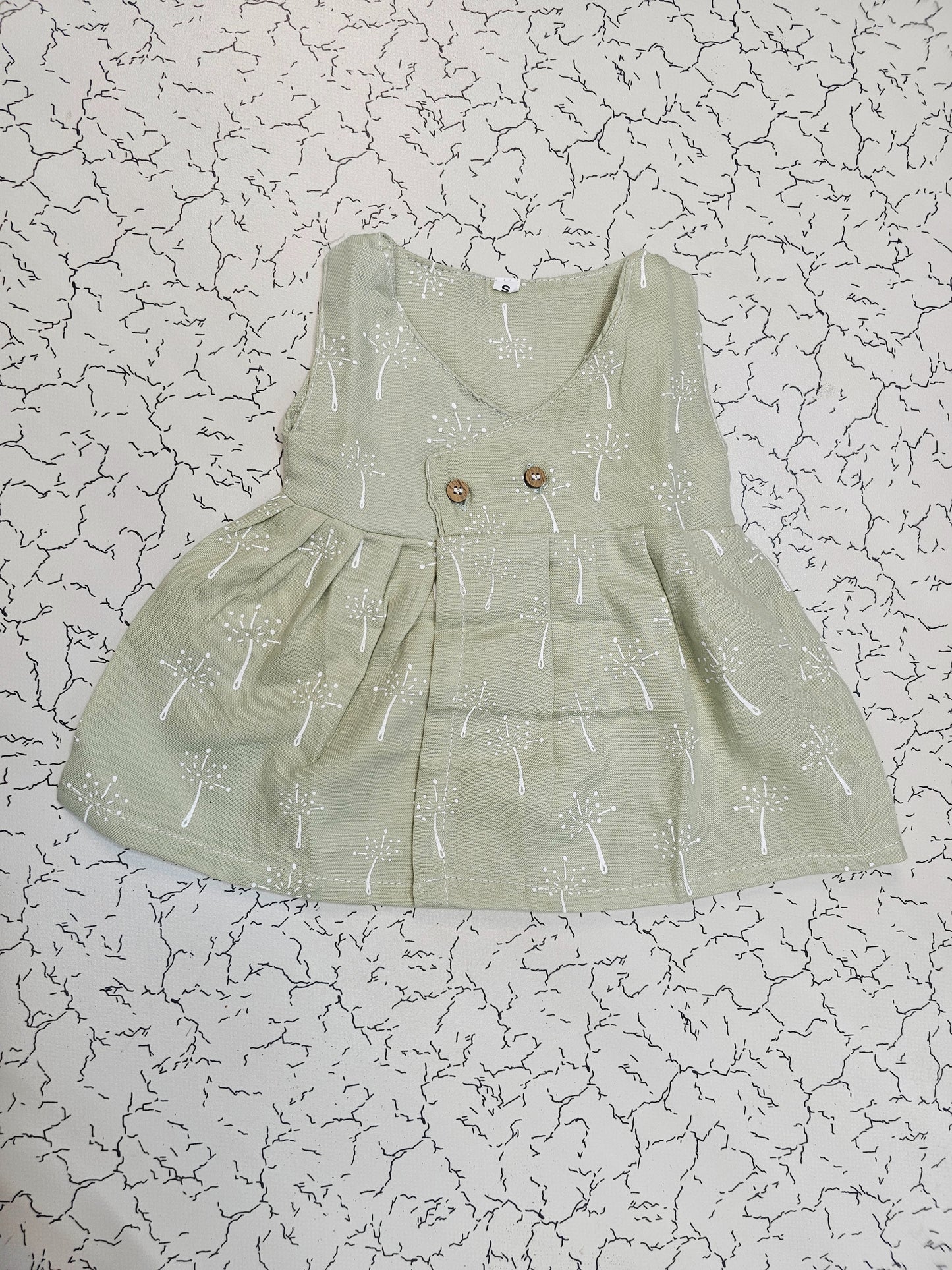 Light green muslin baby jabla frock with white multi print and button design for 0–6 months.