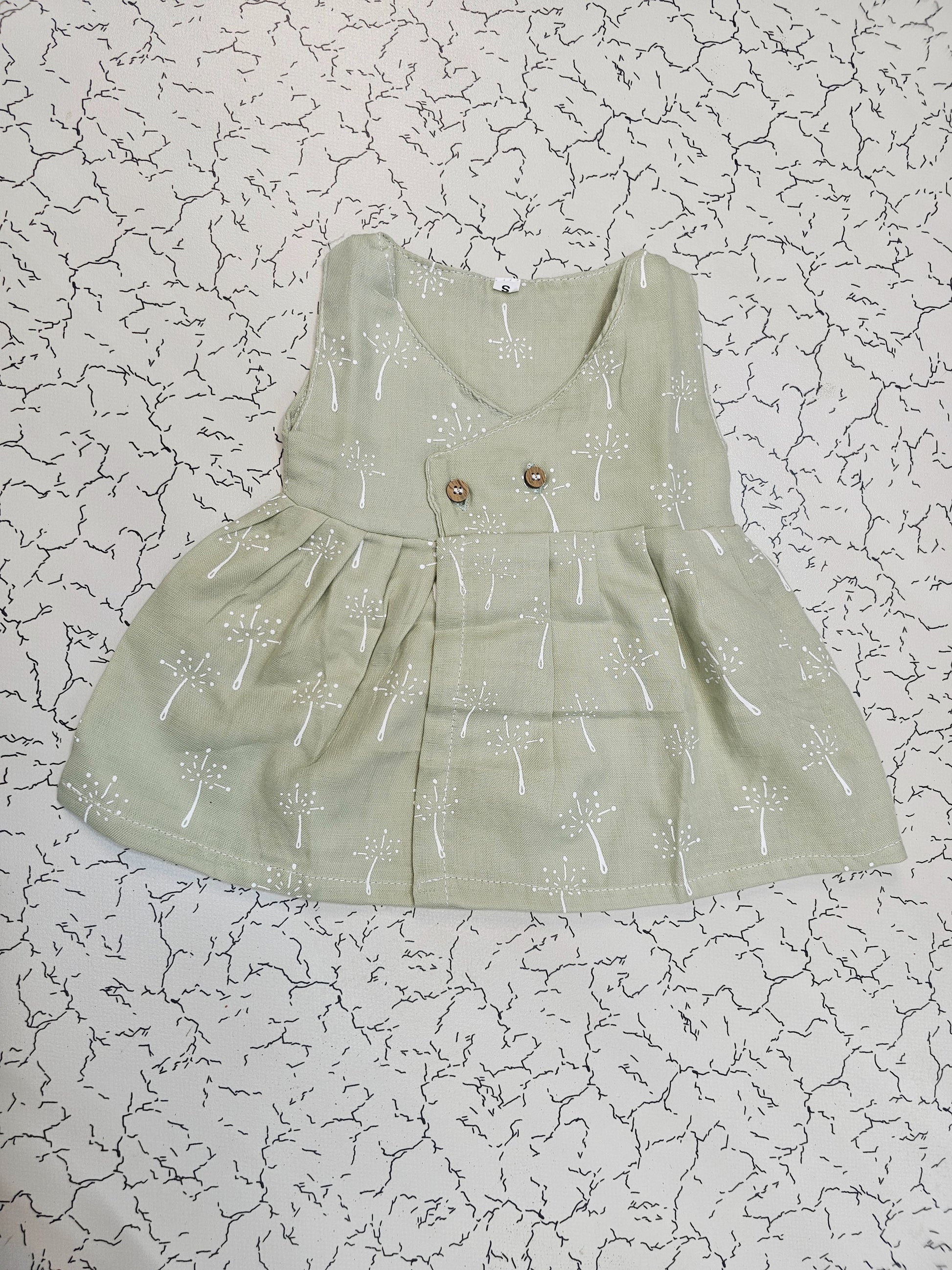 Light green muslin baby jabla frock with white multi print and button design for 0–6 months.