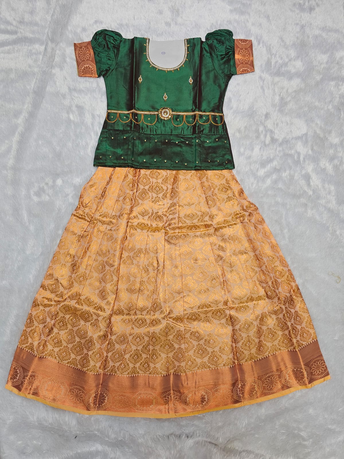 Bottle green semi silk top with antique gold bridal silk skirt pattu pavadai for girls featuring puff sleeves, waist belt detailing and double chain stone neck work by Sri Thulir Tex
