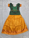 Bottle green semi silk top with mustard gold bridal silk skirt pattu pavadai for girls featuring puff hand sleeves, waist belt design and double chain neck stone work by Sri Thulir Tex