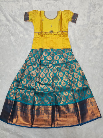 Bright yellow semi silk blouse with teal blue bridal silk skirt pattu pavadai for girls featuring puff sleeves, waist belt design and double chain neck stone work