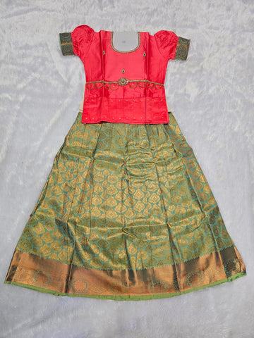 Coral pink semi silk top with teal green bridal silk skirt pattu pavadai for girls featuring puff hand sleeves, waist belt design and double chain stone neck work by Sri Thulir Tex