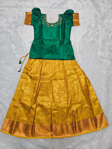 Emerald green semi silk blouse with mustard bridal silk skirt pattu pavadai for girls featuring zari border, puff sleeves and waist belt stone work