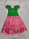Emerald green semi silk top with rose pink bridal silk skirt pattu pavadai for girls featuring puff sleeves, waist belt detailing and double chain stone neck work by Sri Thulir Tex