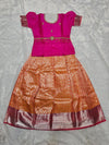Hot pink semi silk top with orange bridal silk skirt pattu pavadai for girls featuring puff sleeves, waist belt detailing and double chain stone neck work by Sri Thulir Tex