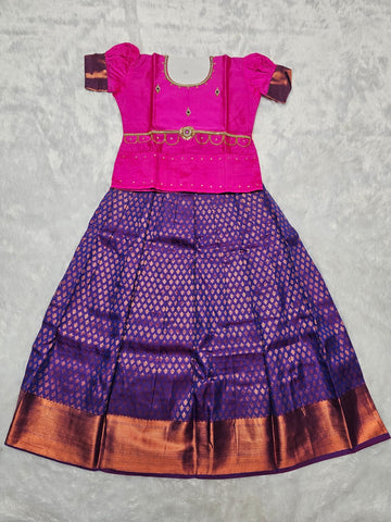 Hot pink semi silk blouse with royal purple bridal silk skirt pattu pavadai for girls featuring puff sleeves, zari border and stone work waist belt