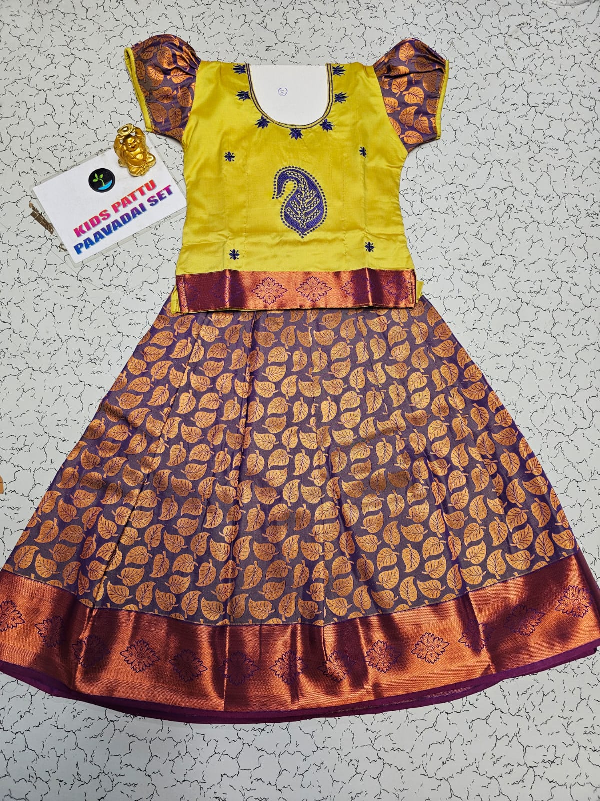 Kids pattu pavadai set with yellow semi-silk top and purple leaf patterned silk skirt by Sri Thulir Tex