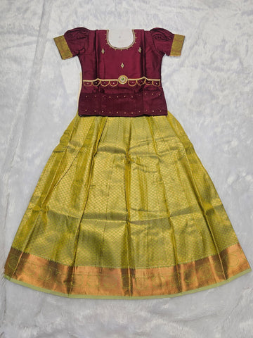 Maroon semi silk top with olive green bridal silk skirt pattu pavadai for girls featuring puff hand sleeves, waist belt detailing and double chain neck stone work by Sri Thulir Tex