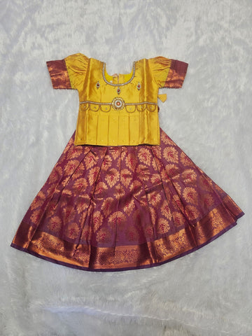 Mustard yellow semi silk top with maroon bridal silk skirt pattu pavadai for girls featuring puff hand sleeves, waist belt detailing and double chain stone neck stone work by Sri Thulir Tex