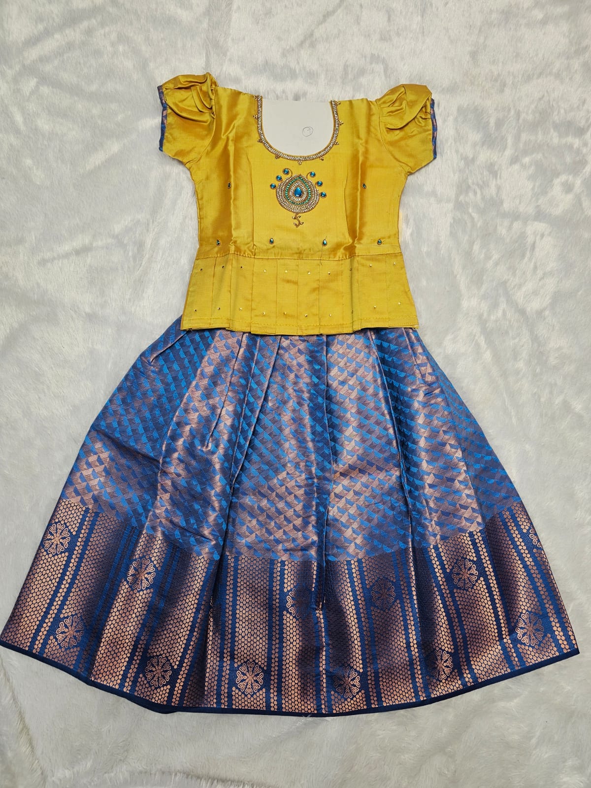 Golden yellow semi silk top with royal blue bridal silk skirt pattu pavadai for girls featuring puff sleeves and double chain stone neck work, traditional South Indian ethnic wear by Sri Thulir Tex