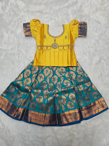 Mustard yellow semi silk blouse with teal blue bridal silk skirt pattu pavadai for girls featuring puff sleeves, waist belt design and double chain neck stone work