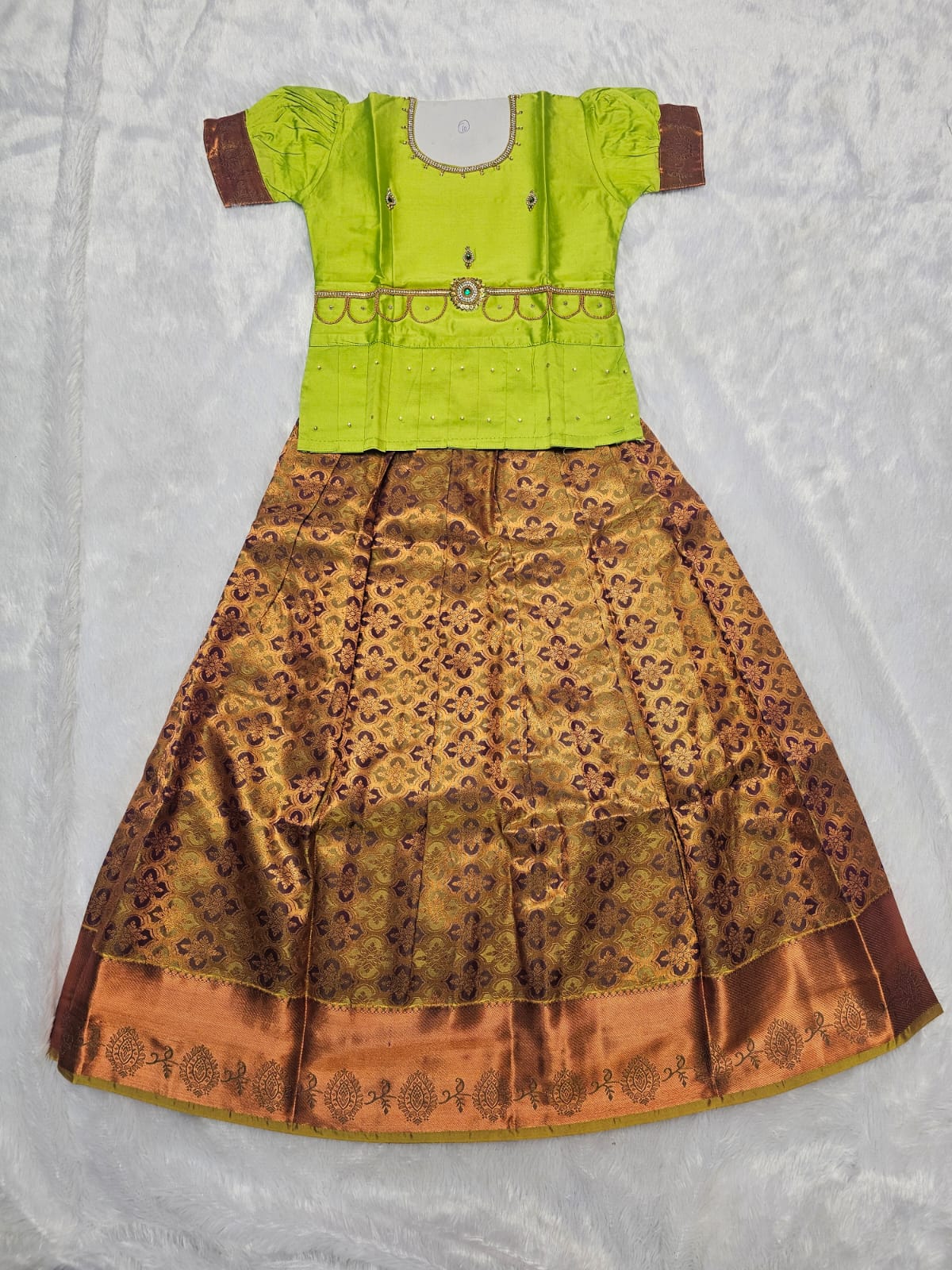 Parrot green semi silk top with antique gold bridal silk skirt pattu pavadai for girls featuring puff hand sleeves, waist belt detailing and double chain neck stone work by Sri Thulir Tex