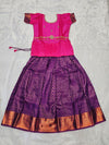 Pink semi silk top with purple bridal silk skirt pattu pavadai for girls featuring puff hand sleeves, waist belt design and double chain neck stone work by Sri Thulir Tex