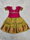 Rani pink semi silk top with green bridal silk skirt pattu pavadai for girls featuring puff hand sleeves, waist belt design and double chain stone neck work by Sri Thulir Tex