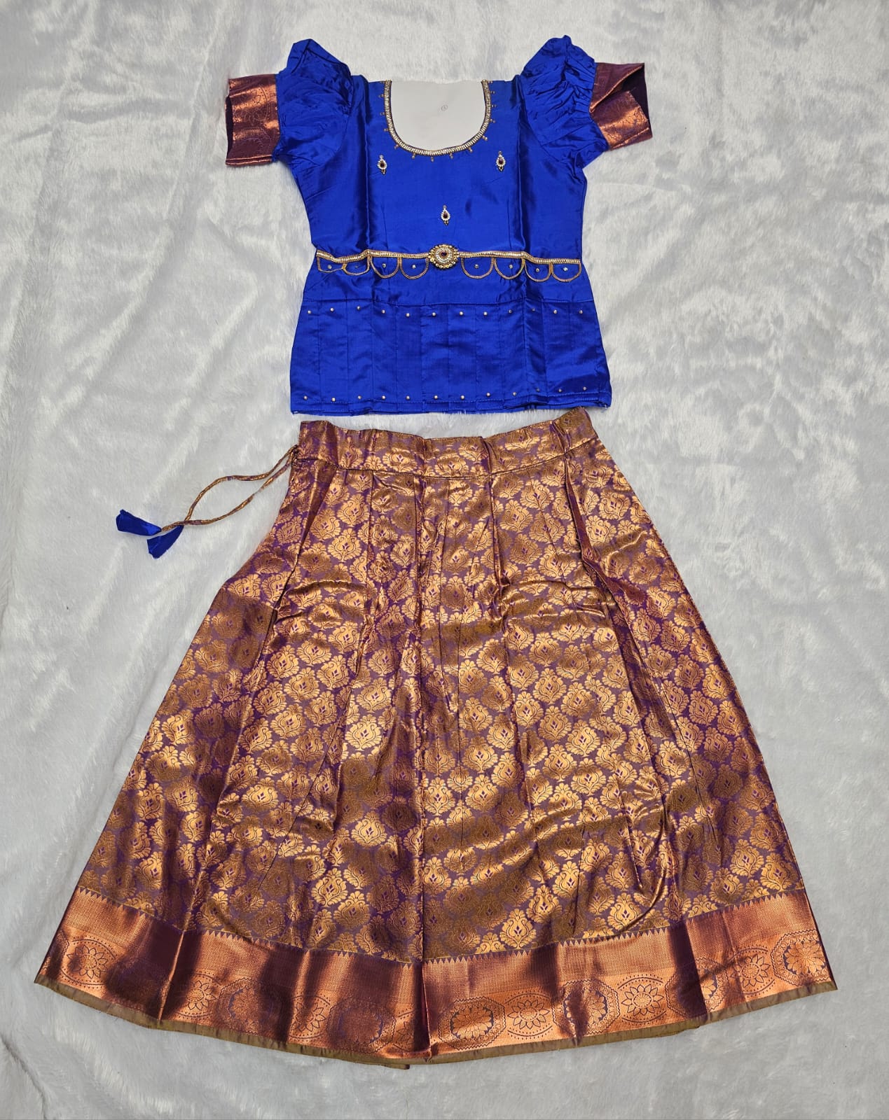 Royal blue semi silk top with antique gold bridal silk skirt pattu pavadai for girls featuring puff sleeves, waist belt design and double chain stone neck work by Sri Thulir Tex