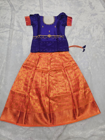 Royal blue semi silk top with orange bridal silk skirt pattu pavadai for girls featuring puff hand sleeves, waist belt detailing and double chain neck stone work by Sri Thulir Tex