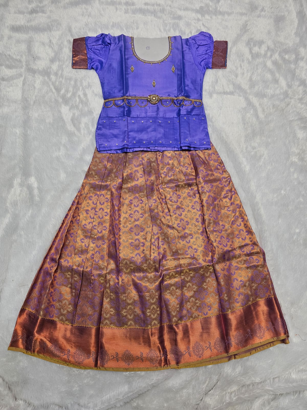 Royal violet semi silk top with copper gold bridal silk skirt pattu pavadai for girls featuring puff sleeves, waist belt design and double chain neck stone work by Sri Thulir Tex